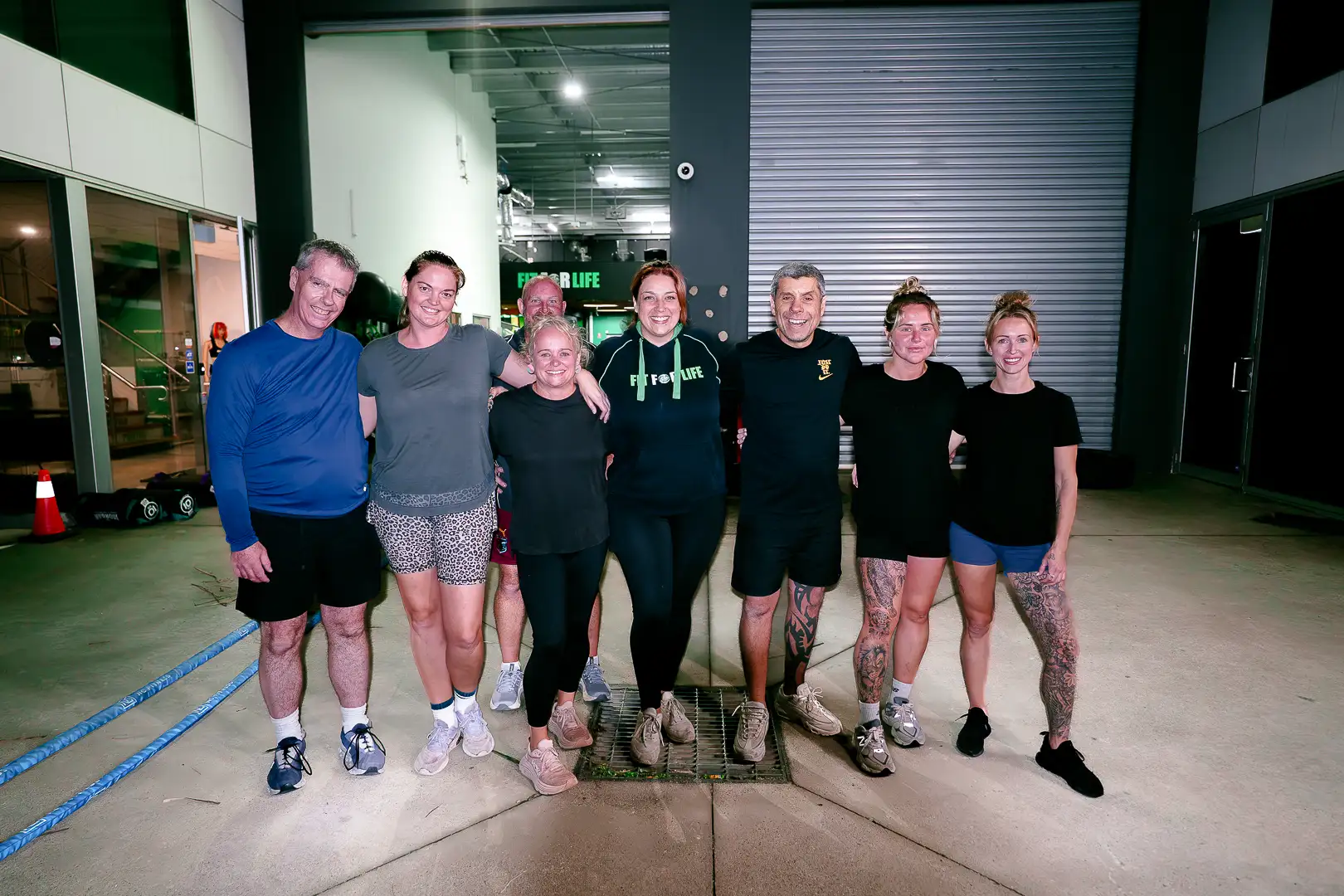 A group of Fit For Life members and coaches standing together in the gym
